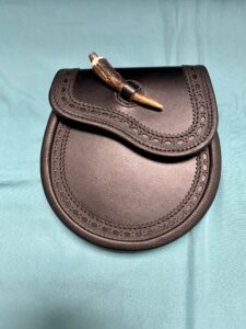 Black leather sporran with etched edging, stag horn closure and lined inside in suede. Made in Scotland. Scottish Treasures